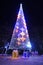 Public Christmas tree with presents illuminated by lights and decorations