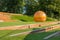 Public city park with long benches and wooden globe modern design.