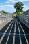 Public footbridge in stark shadowed sunlight. Long stripes of black shadow follow the contours of the bridge.