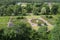 Public park covered with trees and grass in the city with a fountain in the middle and people walking, view from above.