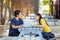 At the public park, a happy young couple using a laptop sits at a table