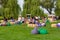 Public picnic outdoors. People rest on a green lawn on a hot summer day