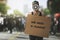 public protest and riots in the city streets. woman with megaphon and cardboard poster in hands on protesters crowd background