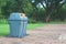 Public recycle bins or segregated waste bins located on concrete floor beside walkway in public park.