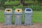 Public recycle bins or segregated waste bins located on concrete floor beside walkway in public park.