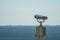 Public stationary binoculars on the seashore, metal binoculars on blurred sea background