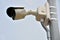 A public surveillance camera installed on a lamp post against a light hazy cloudless blue sky