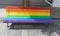 Public wooden bench painted in Rainbow colors as gay pride symbol. Lgbt community support and tolerance in urban street with