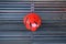 A public wooden seat with a red painted metallic handle in the shape of a leaf