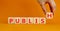 Publish symbol. The concept word Publish on wooden cubes. Beautiful orange table, orange background, copy space. Businessman hand