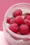 Pudding chia with coconut milk and raspberries on the pink background.