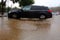 The puddle is gradually turning into a flood, rainwater covers the wheels of the car. Rain in Israel