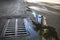 Puddle on the pavement, palm trees reflected in the water. water flows into the sewer drain