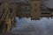 Puddle reflections of walls, windows, roofs of buildings and blue sky on wet asphalt pavement of city street road after summer