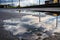 puddle of water on asphalt after rain storm, with reflection of cloudy sky