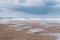 Puddles on a beach at low tide with grey clouds