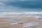 Puddles on a beach at low tide with low heavy grey clouds