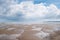 Puddles on a beach at low tide with white fluffy clouds