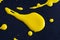 The puddles of an bright yellow oil paint spill. Watercolor yellow drop splash. Splatter of ink drops on black paper background.