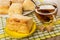 Puff cookies in dish, cup of tea, cookie in saucer on napkin on wooden table