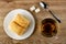 Puff cookies in white plate, sugar cubes, spoon, transparent cup with tea on wooden table. Top view