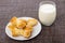 Puff pastry in form bow-knot in saucer, glass of milk on mat