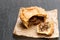 Puff pastry steak pie on baking paper on black stone backgroung