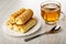 Puff rolls with creamy filling in plate, spoon, transparent cup with tea on table