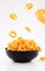 Puffed corn rings chips in black bowl on white background