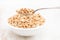 Puffed spelt in white bowl on wooden background