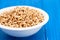 Puffed spelt in white bowl on wooden background