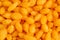 Puffy orange corn sticks with chili closeup, top view. Fast food background.