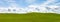 Puffy white clouds and blue sky over a huge beautiful idyllic vibrant green grassy field with gently rolling hills in the backgrou