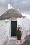 Puglia, Italy. Traditional conical roofed trullo house on a street in Alberobello.