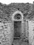 Puglia, Italy. Traditional conical roofed trullo house on a street in Alberobello. Photographed in monochrome.