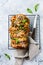 Pull-apart bread with Italian pasta pesto, basil and parmesan cheese in baking form over old light concrete background.