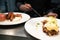 Pulled pork topped with poached egg and garnished with hollandaise sauce and breakfast sausages waiting to be served at a