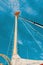 pulley with a rope on a classic sailing boat and a background of blue water. Detailed view of the classic mast of a