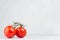 Pulpy red tomatoes on branch in light soft white modern kitchen interior with copy space.