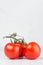 Pulpy red tomatoes on branch in light soft white modern kitchen interior with copy space, vertical, closeup.