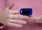 pulse oximeter on the hand of a girl in a pink sweater