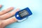 Pulse oximeter to measure pulse rate and oxygen levels isolated on blue background. Medical concept. Diagnosing coronavirus