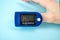 Pulse oximeter to measure pulse rate and oxygen levels isolated on blue background. Medical concept. Diagnosing coronavirus