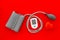 Pulsimeter on the desk of the doctor for diagnostics of cardiac disease on red background top view