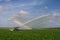 Pump trucks irrigating fields near Homestead, Florida creating rainbow in spray