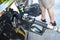 Pumping gas - closeup of gas pump nozzle inserted into to car gas tank with legs of customer in shorts in background