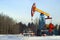 A pumpjack over an oil well in a winter wooded landscape