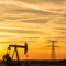 Pumpjack and transmission tower at sunset symbolizing energy transition