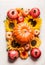 Pumpkin with apples, flowers, pomegranate and sunflowers on white table, top view. Autumn or late summer layout composing.