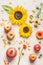 Pumpkin with apples, flowers, pomegranate and sunflowers on white table, top view. Autumn or late summer layout composing.